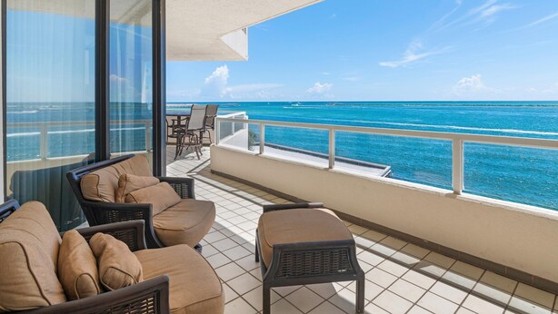 A balcony with a view of the ocean, furnished with chairs and a table. - East Pass 309 (Destin)