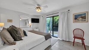 Quarto com cama, televisão, cadeira e um quadro na parede.