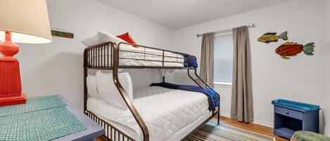 A bunk bed room with a red lamp, a striped rug, and wall art.