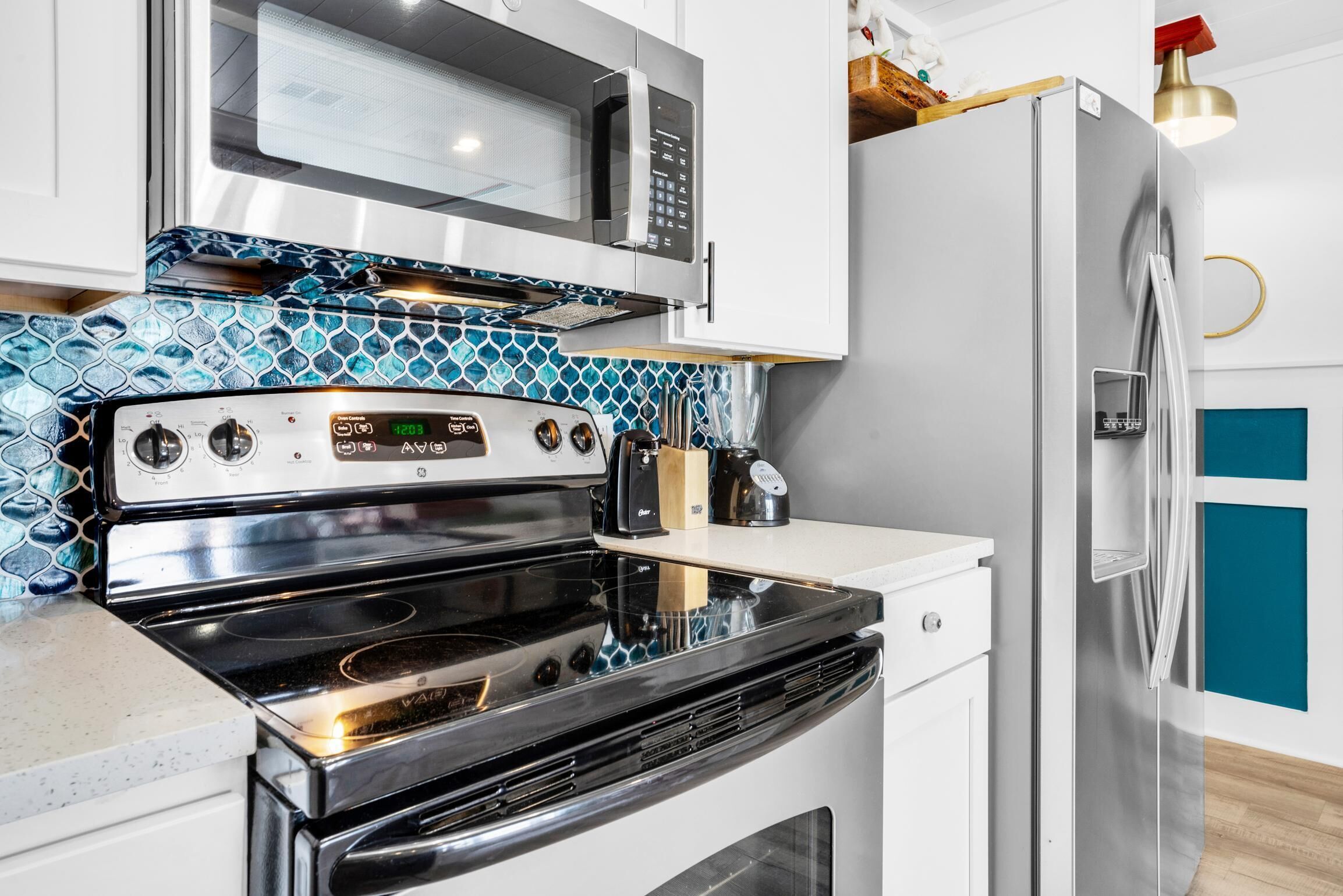 A kitchen with a stainless steel stove, a microwave, and a refrigerator.