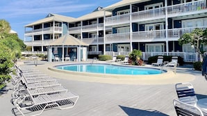 A multi-story hotel with a pool area, including lounge chairs and a gazebo. - Summer Breeze 203 (Miramar Beach)