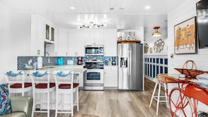 A modern kitchen with white cabinetry, a central island, and a stainless steel refrigerator. - Summer Breeze 203 (Miramar Beach)