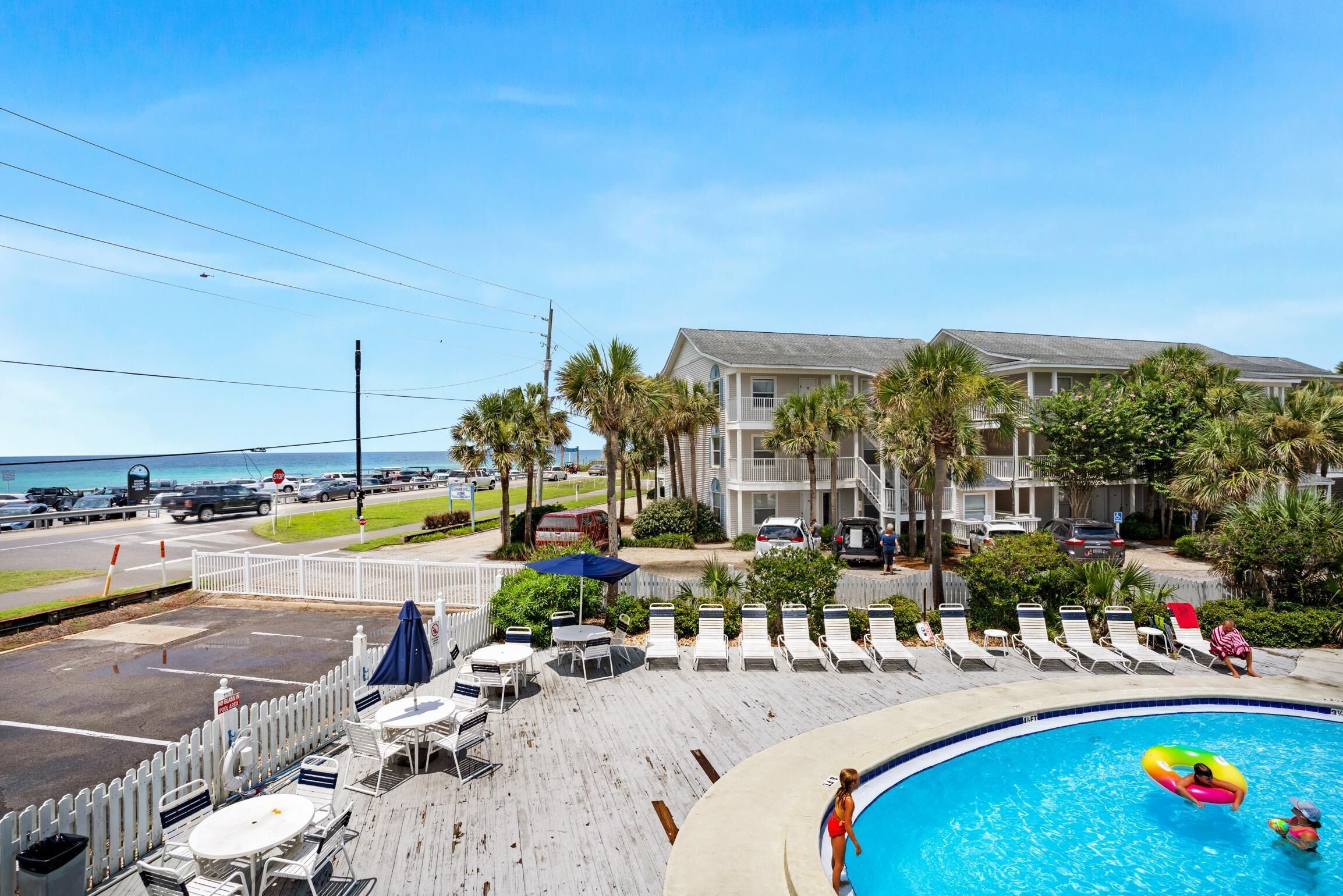 A pool area with lounge chairs and a view of the ocean.