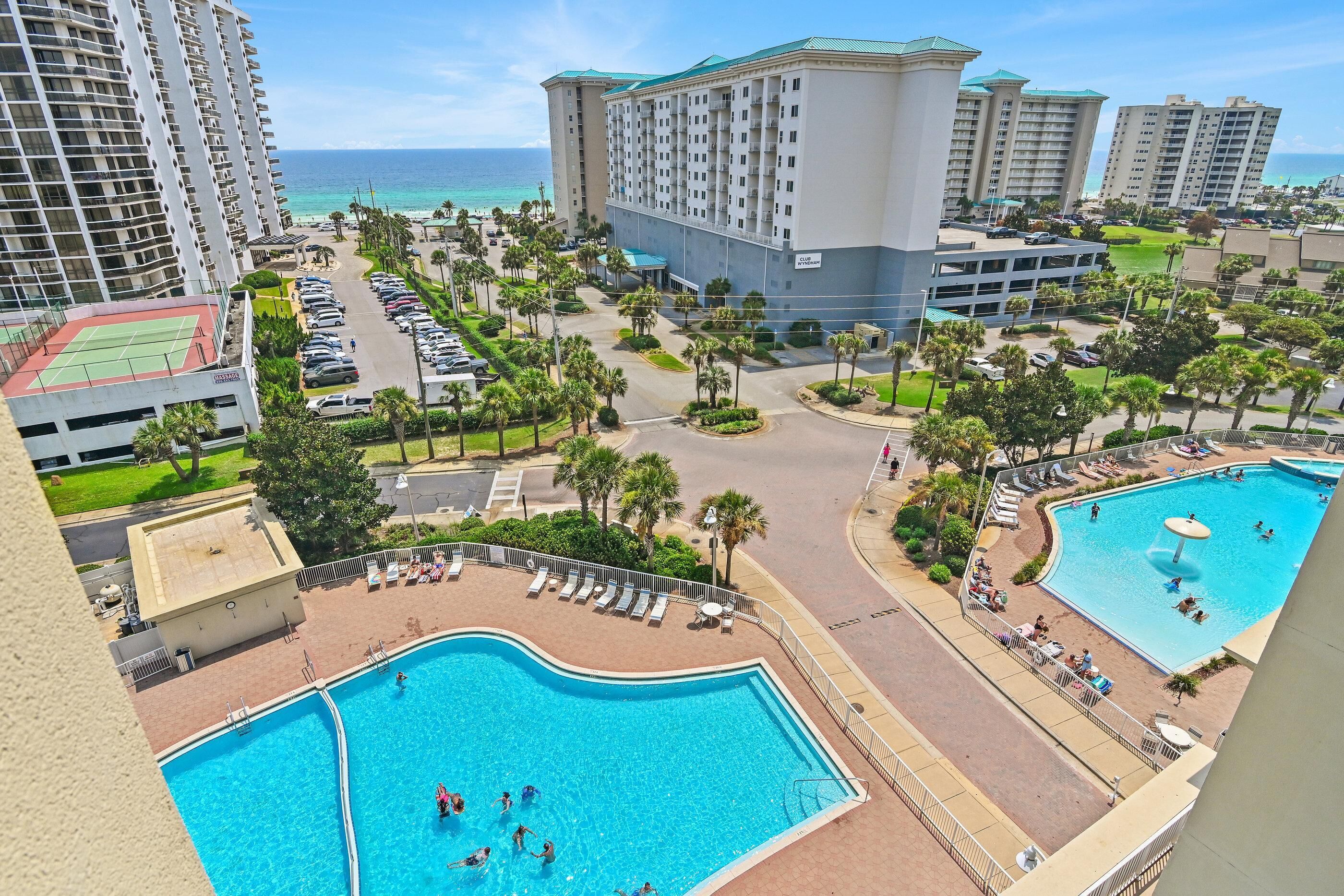 Ein Resort mit mehreren Swimmingpools, einem Tennisplatz und Blick auf den Ozean.