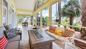 A covered patio area with a sofa, chairs, and a table.