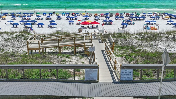 A beach with a wooden boardwalk leading to a private beach area.
