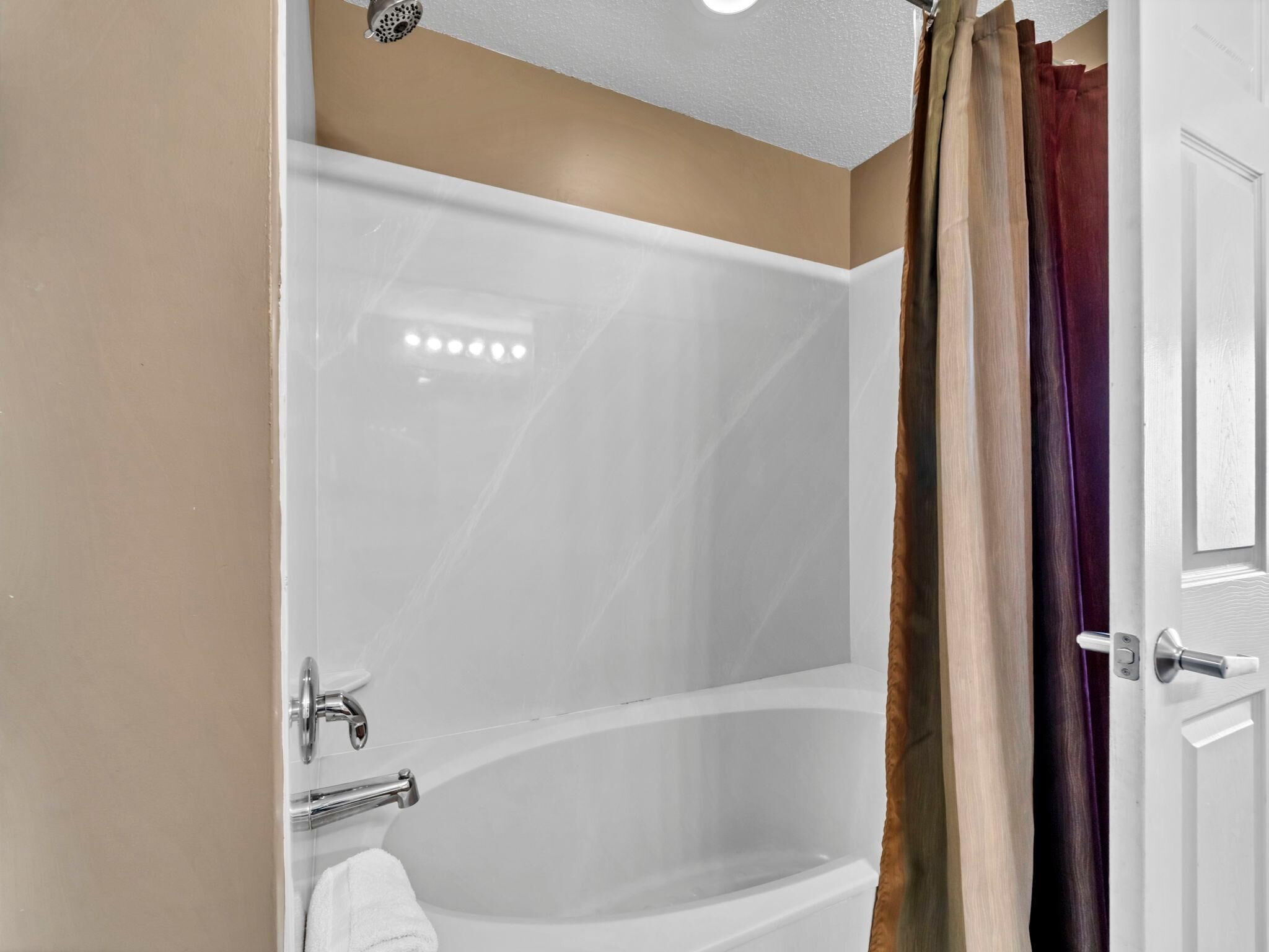 A modern bathroom with a glass-enclosed shower, a white bathtub, and a towel rack.