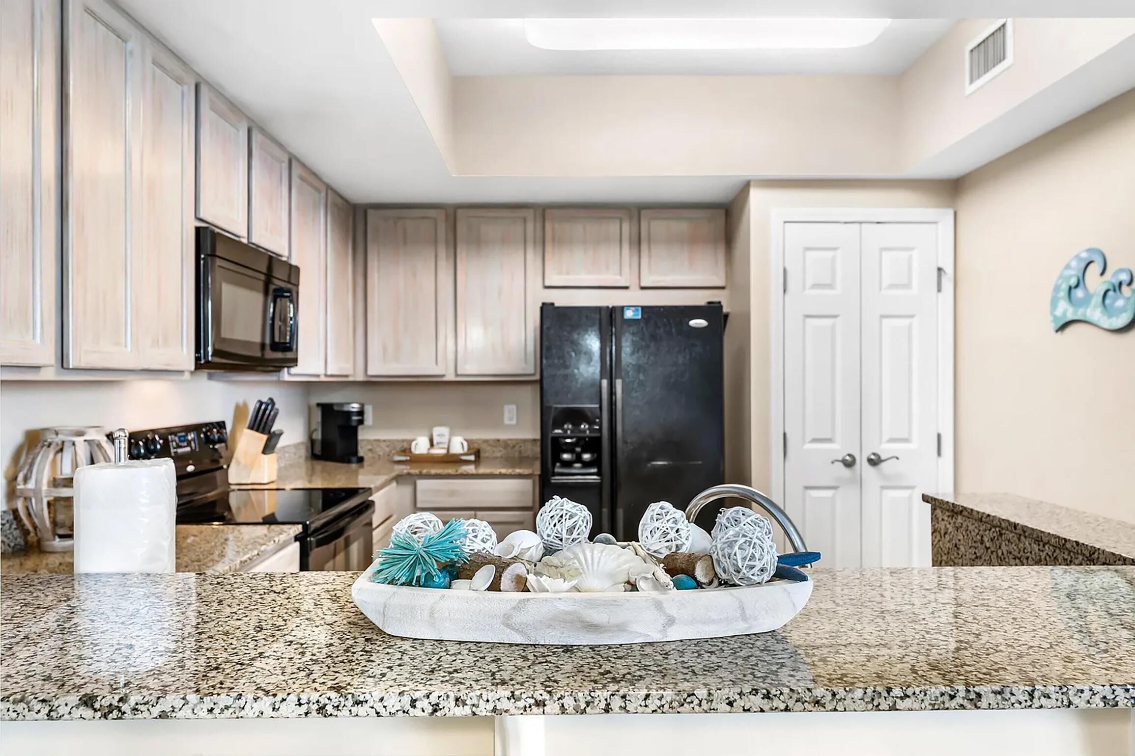 A kitchen with granite countertops, a black refrigerator, and wooden cabinets.