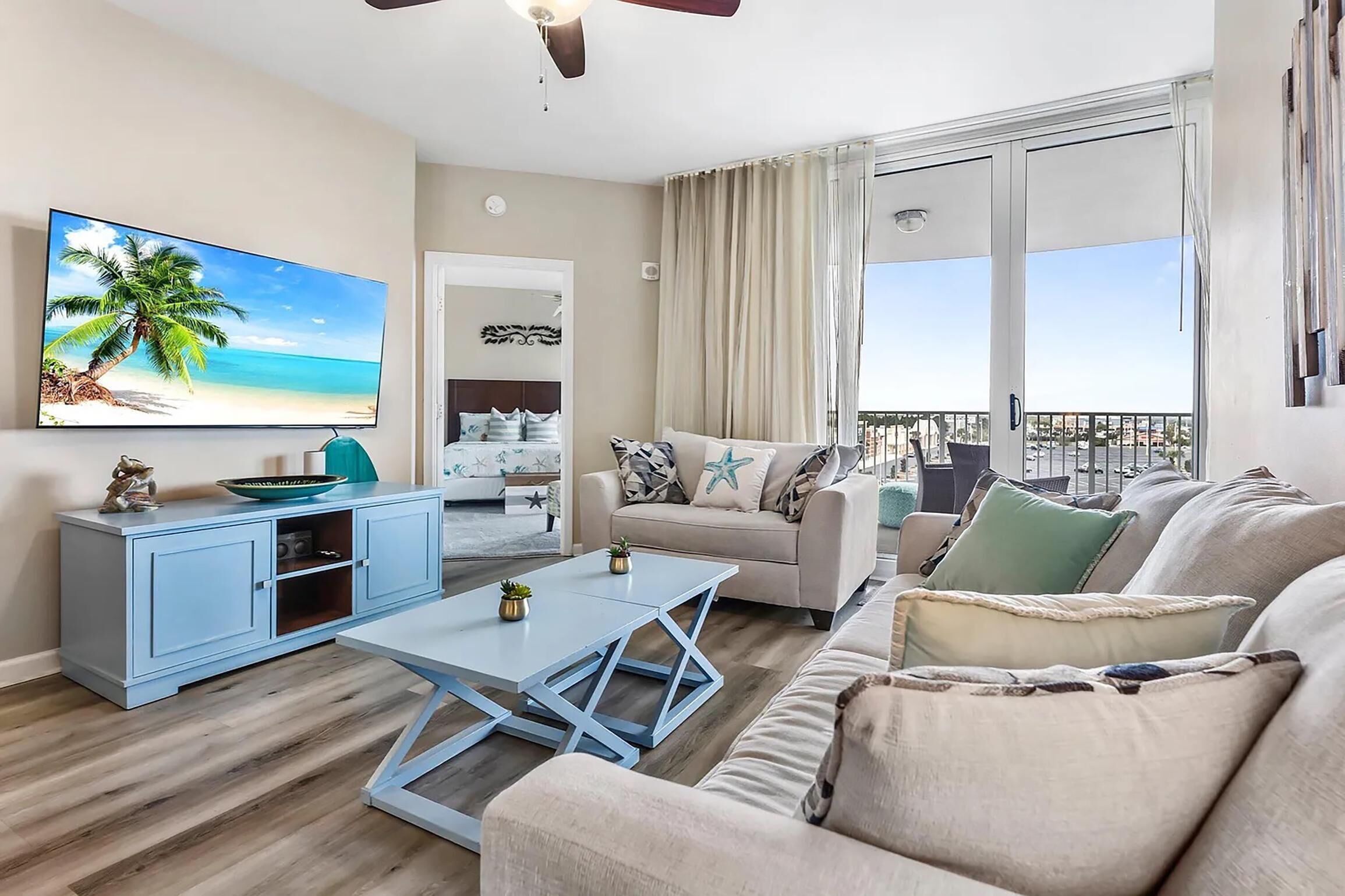Een moderne woonkamer met een grote televisie, een bank, een salontafel en een balkon met uitzicht.