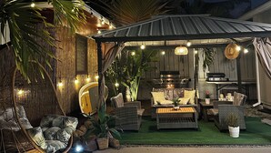 An outdoor patio area with wicker furniture, a hanging chair, and string lights. - Beach House,2 minutes walking to the beach and Restaurant The Beach House by 604 (Waianae)
