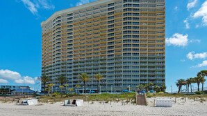 A high-rise hotel with multiple balconies, located on a beach with palm trees and beach umbrellas. - Boardwalk 209 (Panama City Beach)