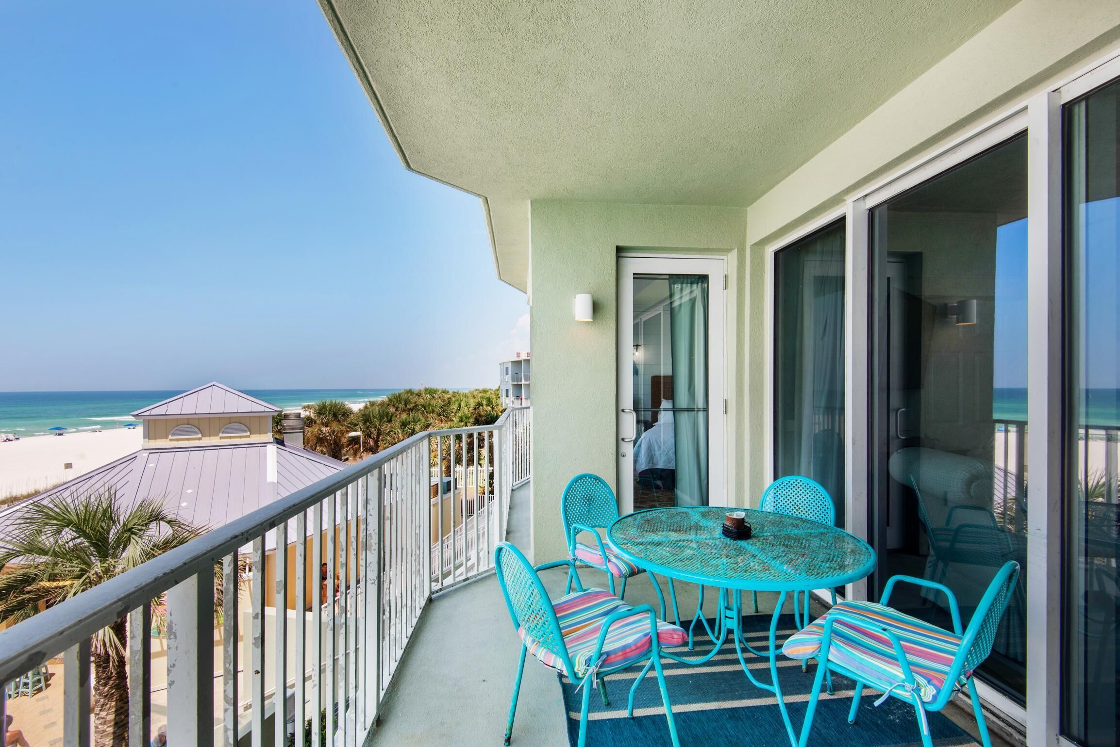 Ein Balkon mit Tisch und Stühlen, der Blick auf einen Strand und den Ozean bietet.