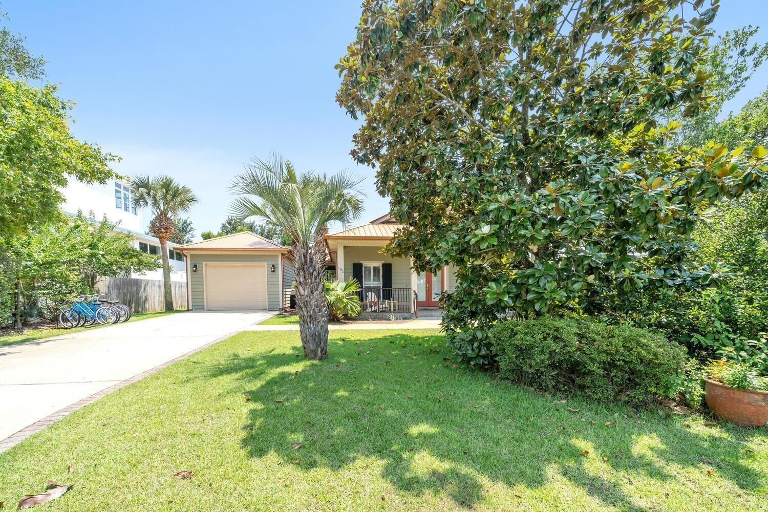 A residential property with a garage, a lawn, and a large tree.