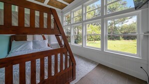 A bunk bed in a room with large windows and a view of a garden. - Drift Away (Santa Rosa Beach)