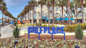 A sign reading "GULF PLACE" with a row of palm trees and a building with balconies in the background. - Drift Away (Santa Rosa Beach)