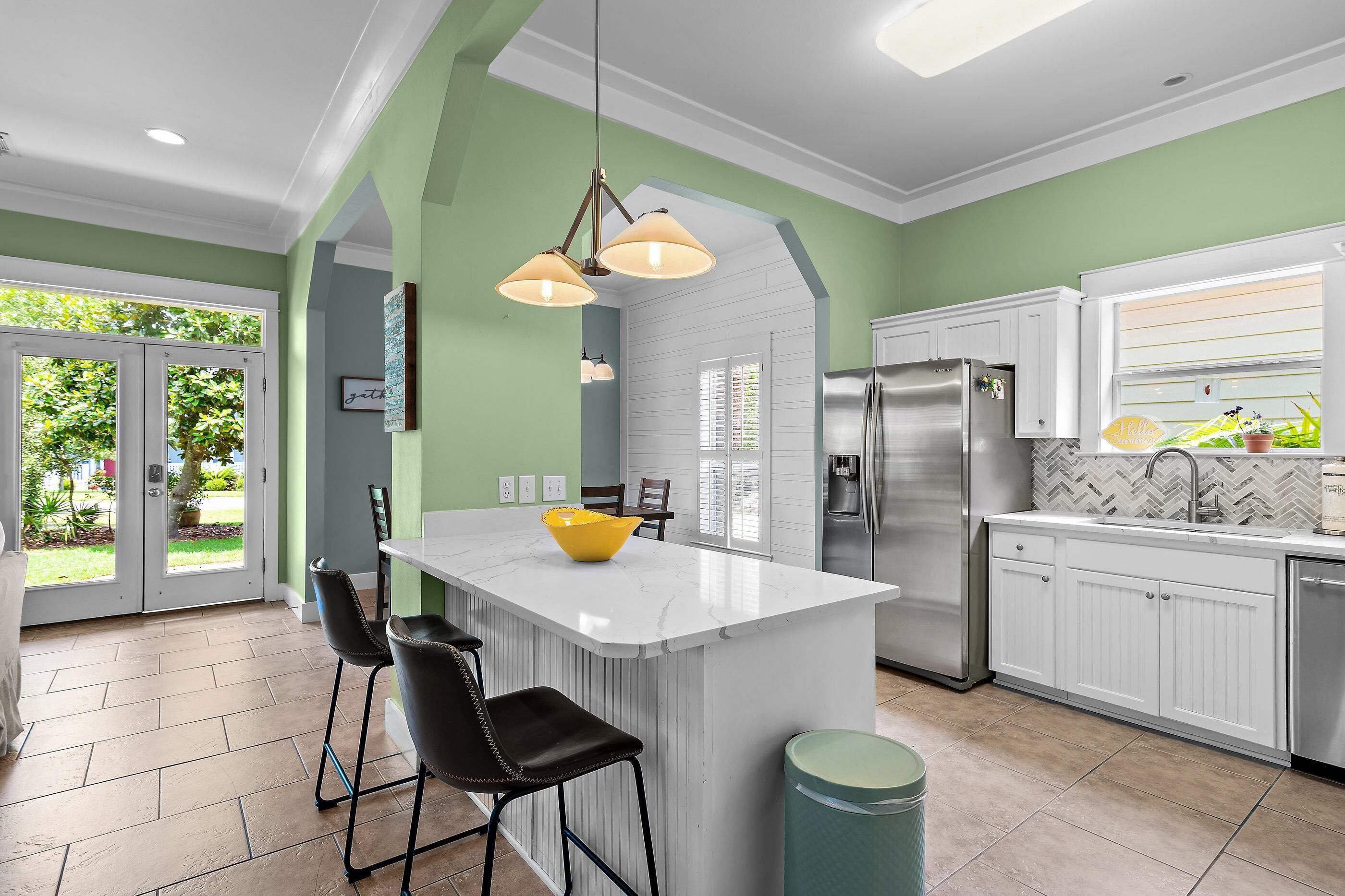 A modern kitchen with a central island, stainless steel appliances, and a green accent wall.