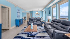 A spacious living room with a black leather sofa, a wooden coffee table, and a blue accent wall.