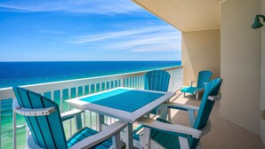 A balcony with a table and chairs, overlooking a clear blue sea.