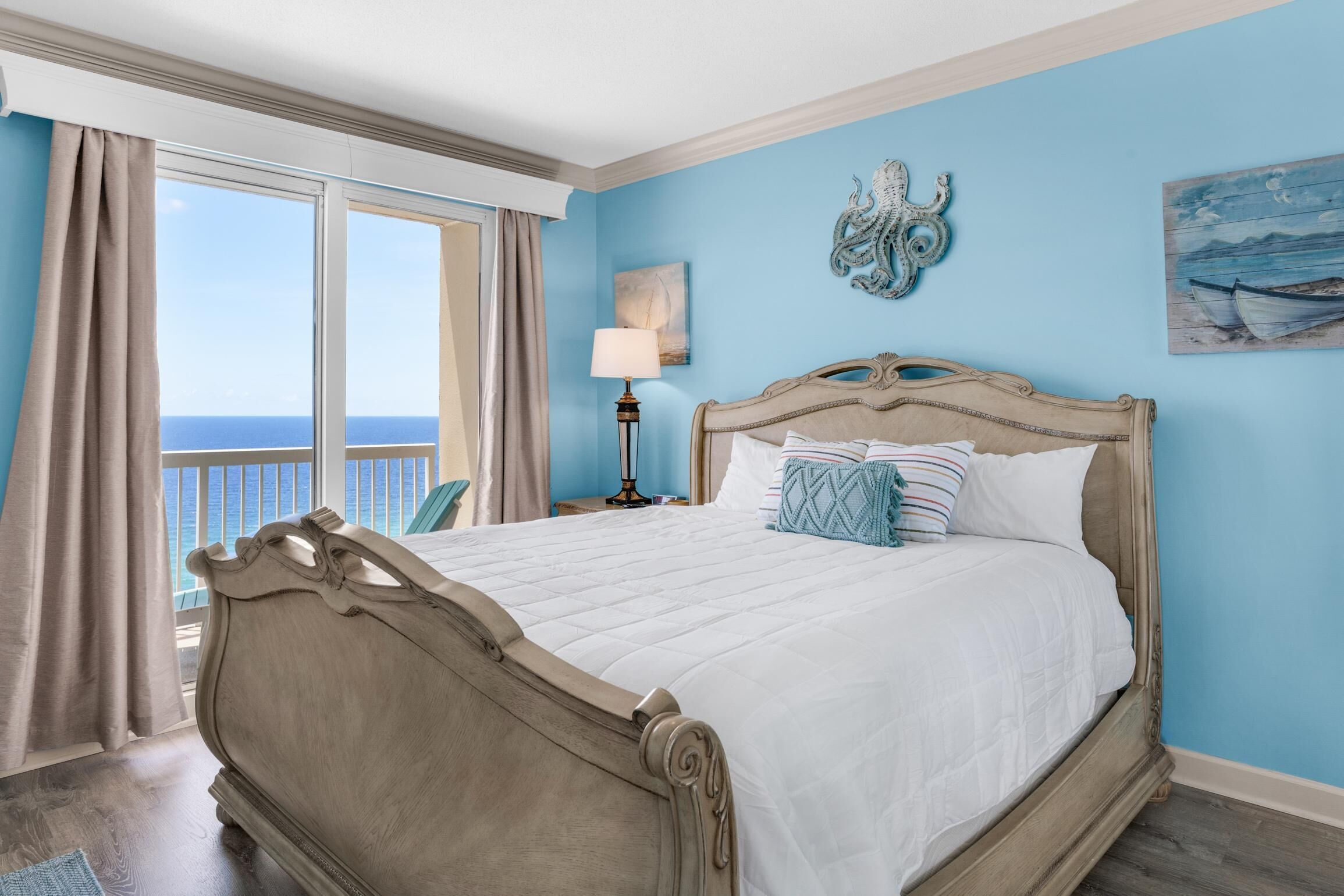 Een slaapkamer met een groot bed, uitzicht op zee en een balkon.