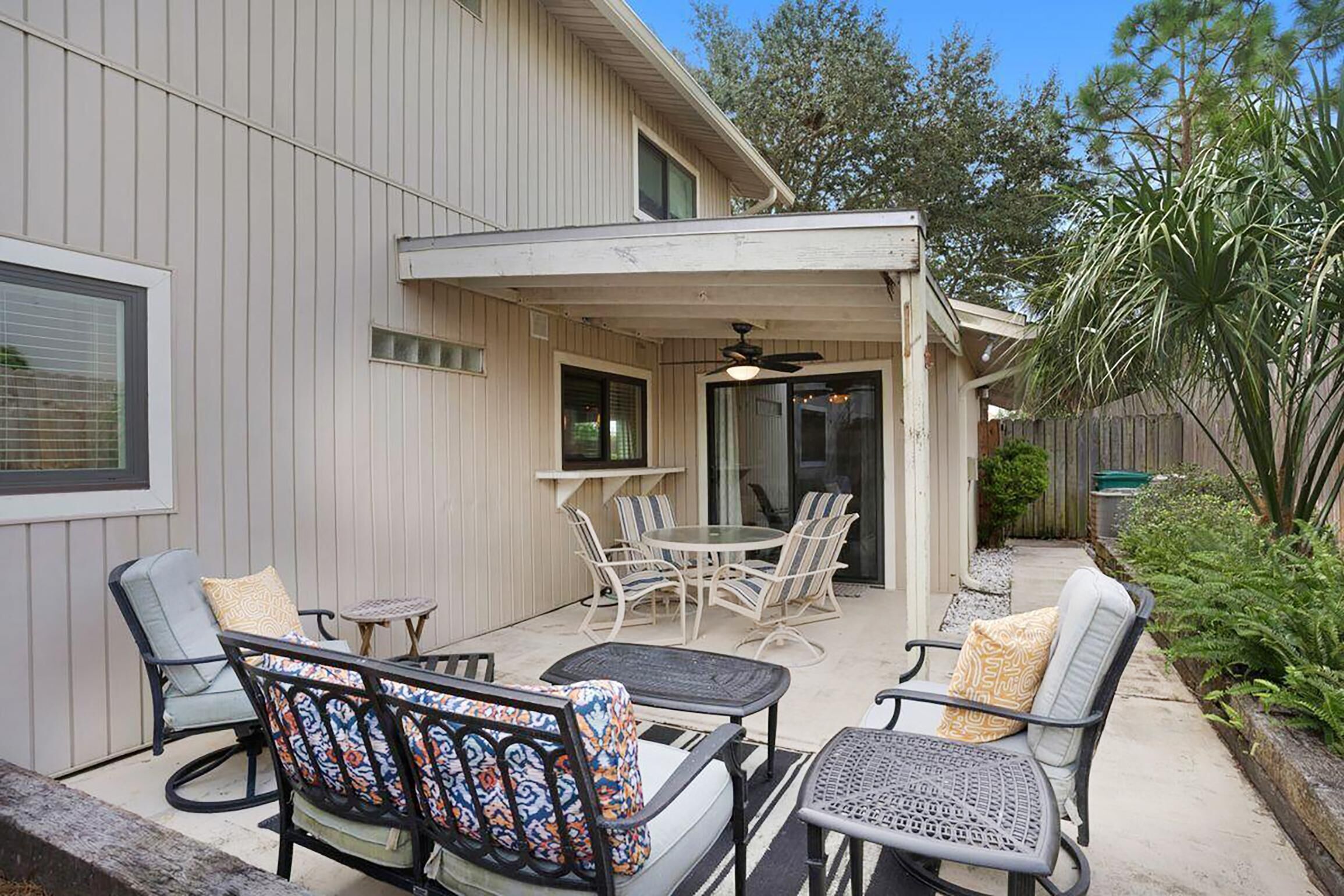 A covered patio with outdoor furniture, a ceiling fan, and a view of the backyard.