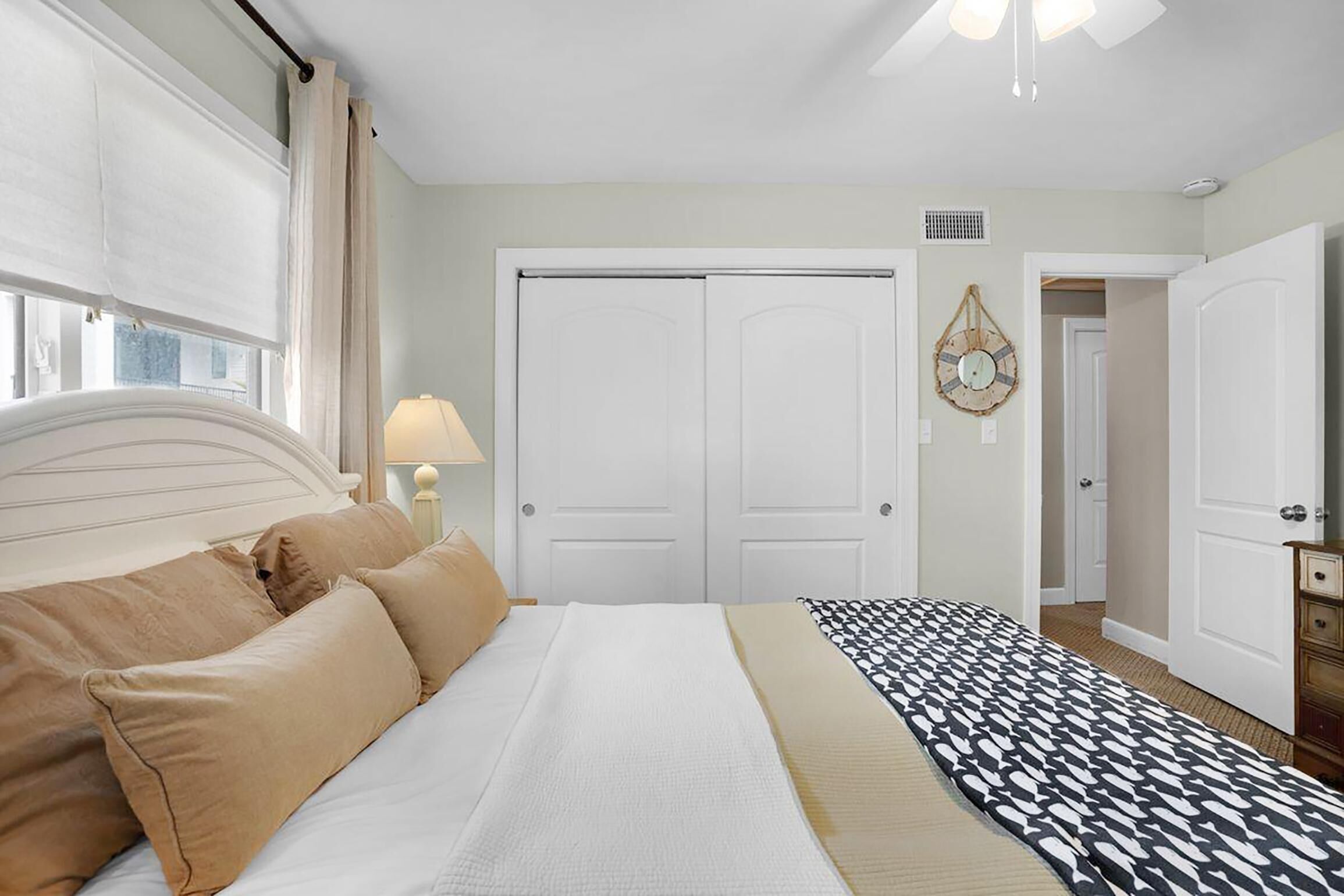 Un dormitorio con una cama, una mesita de noche, una lámpara, un tapete estampado y una puerta.