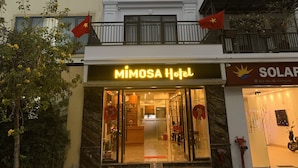 A hotel with a prominent entrance, a balcony with railings, and a flag. - MIMOSA HALONG HOTEL (Ha Long)