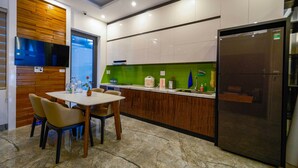 A modern kitchen with a dining area, featuring a marble floor, wooden accents, and a large refrigerator. - MIMOSA HALONG HOTEL (Ha Long)