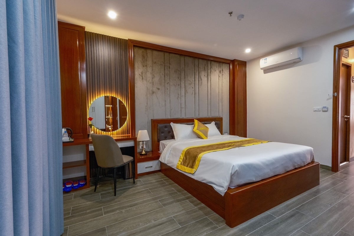 A hotel room with a bed, desk, chair, and a mirror.