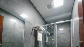 A modern bathroom with a large sink, mirror, and glass-enclosed shower.