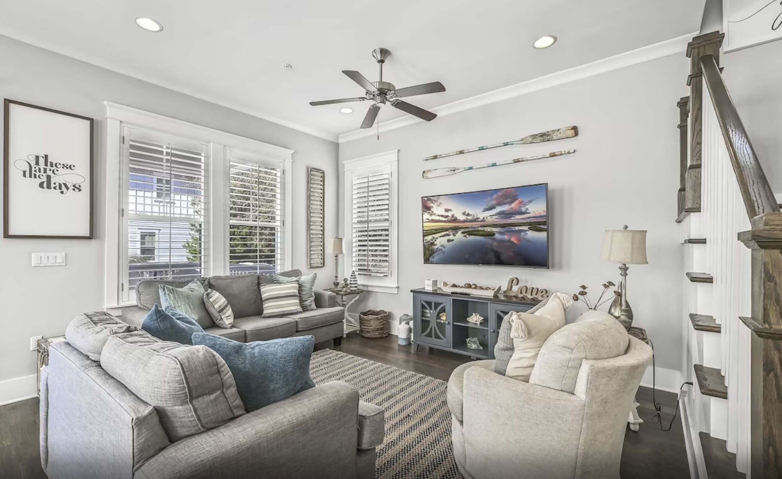 A living room with a sofa, armchairs, a TV, and a ceiling fan.