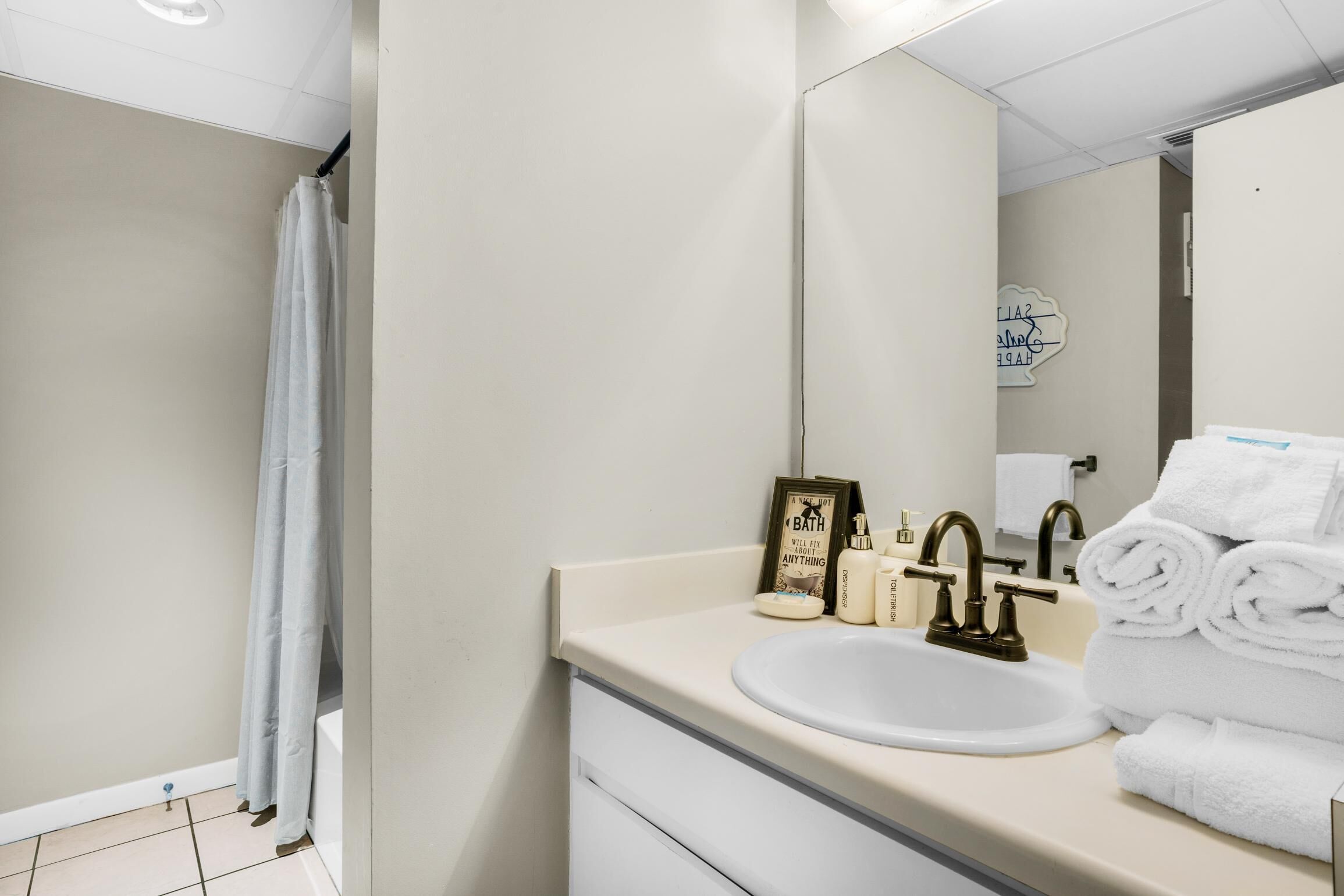 A bathroom with a sink, mirror, and towel stack.