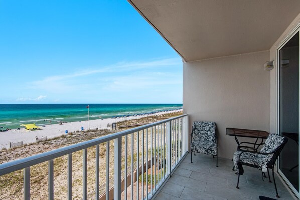 Un balcone con vista sulla spiaggia, due poltrone a motivi decorativi e un tavolino.