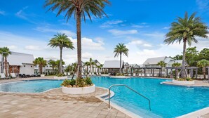 Una piscina con palmeras y sillas de descanso.