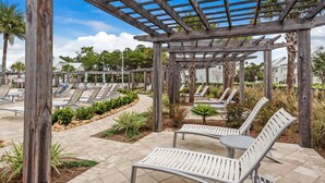 Un espacio de estar al aire libre techado, con pérgolas de madera y sillones de descanso.