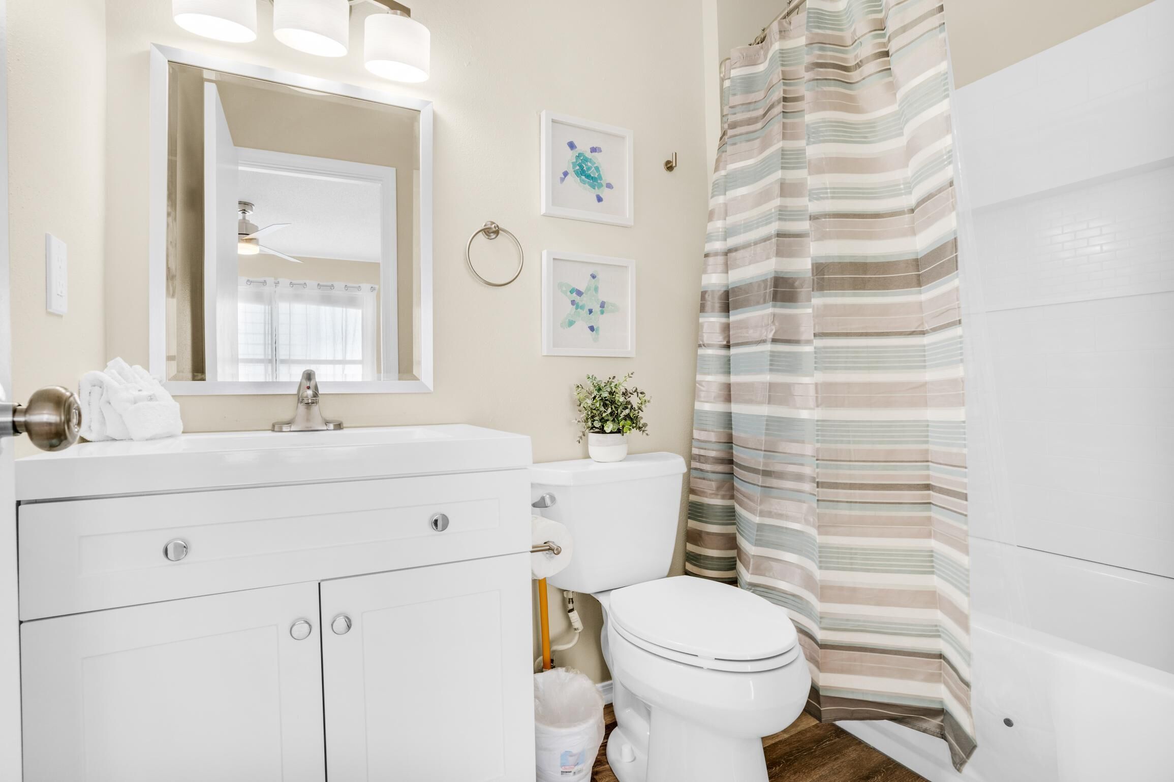 A bathroom with a white sink, toilet, and striped shower curtain.