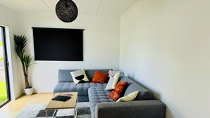 Una sala de estar moderna con un sofá gris, una mesa de centro y una planta grande en maceta.