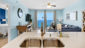 A modern kitchen with a large island, a dining area, and a view of the ocean.