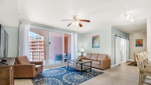 A spacious living room with a sofa, coffee table, and a view of a balcony.