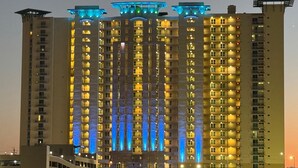 A high-rise building with multiple floors, each illuminated with warm yellow lights. - Aqua Resort 401 - Piece of Serenity (Panama City Beach)