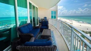 A balcony with wicker furniture, a view of the beach, and a pool. - Aqua Resort 401 - Piece of Serenity (Panama City Beach)