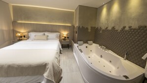 Una habitación de hotel moderna con una cama grande, un área de estar separada y una bañera espaciosa.