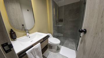 Un baño moderno con un lavamanos grande, inodoro y cabina de ducha de vidrio.