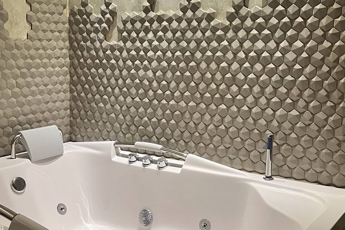 Un baño moderno con una bañera independiente, un perchero y una pared con textura.