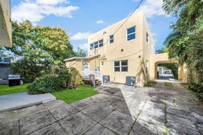 A two-story building with a flat roof, a front porch, and a visible garage door. - Spectacular Estate on Antique Row - Large Groups (West Palm Beach)