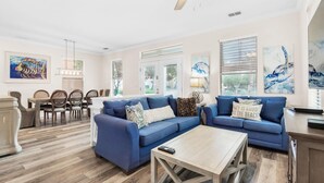 A spacious living room with a blue sofa set, a wooden coffee table, and a ceiling fan. - Destin's Siren Song (Destin)