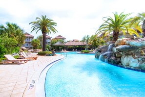 A swimming pool with lounge chairs, palm trees, and a waterfall feature. - Destin's Siren Song (Destin)