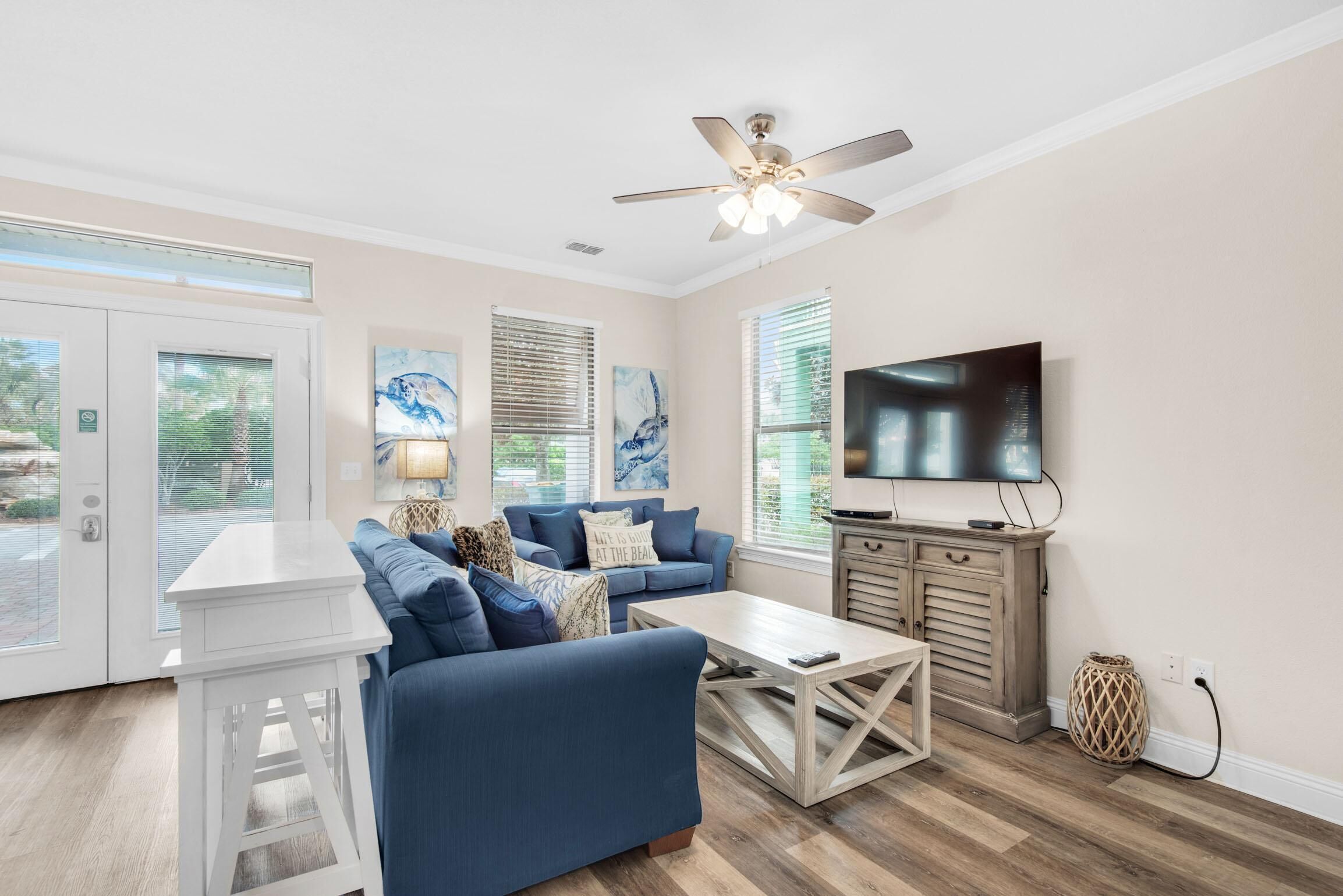 A living room with a blue sofa, a coffee table, a TV, and a ceiling fan.