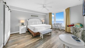 Habitación de hotel con una cama grande, un escritorio, una silla, un globo terráqueo y vista al océano.