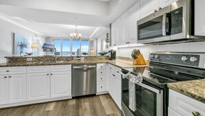 Una cocina moderna con muebles blancos, electrodomésticos de acero inoxidable y encimera de granito.