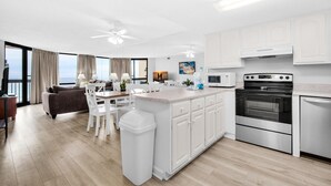 A modern kitchen with white cabinets, a central island, and a built-in oven. - Sundestin 1415 (Destin)